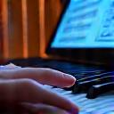Musiker komponiert am Keyboard mit Notenblättern